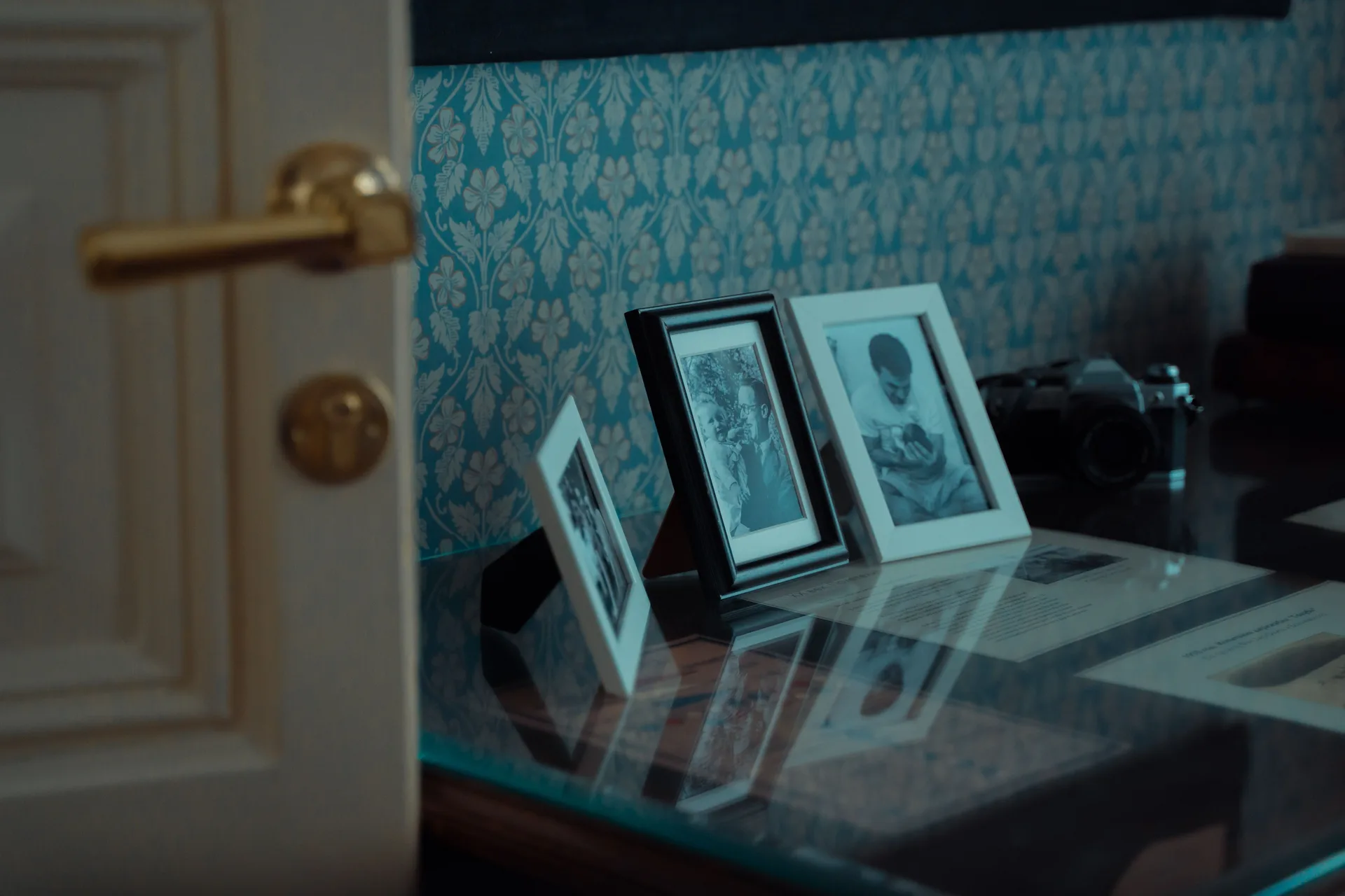 Framed family photographs and a vintage camera on a glass table